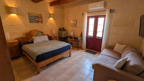 a bedroom with a bed and a couch in a room at Razzett Pepprina Poppy Farm in Xagħra