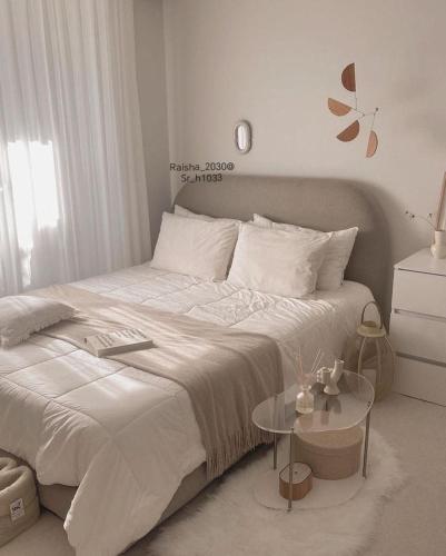 a white bedroom with a large bed and a table at شقق القنفذة بلس in Al Qunfudhah