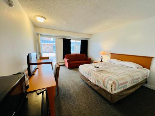 a hotel room with a bed and a desk and a television at Midtown Inn SSK in Saskatoon