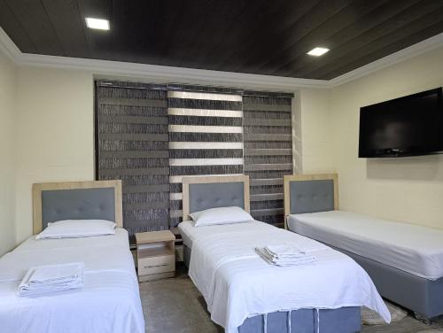 a room with two beds and a flat screen tv at Green house eco hotel Samarkand in Samarkand