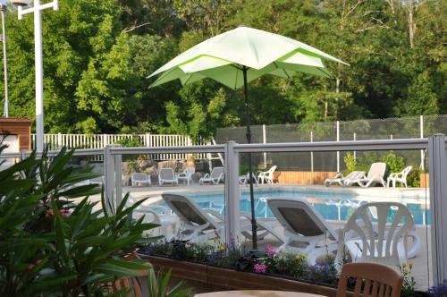 a swimming pool with chairs and an umbrella at Camping La Digue in Chauzon