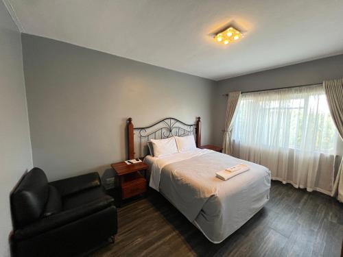 a bedroom with a bed and a chair and a window at Nduna Legacy Apartment in Harare
