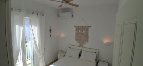 a white bedroom with a bed and a ceiling fan at Naxian Scenery in Glinado Naxos