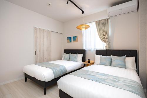 a bedroom with two beds and a window at インギャーラクシー in Miyakojima