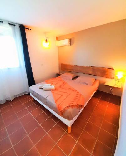 a bedroom with a bed with an orange comforter at Ti Repos - Appartement 2/4 pers| Petit-Havre | Parking in Mare Gaillard