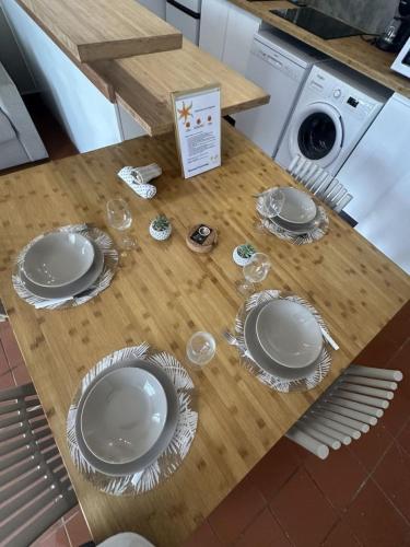 a wooden table with plates and wine glasses on it at Ti Repos - Appartement 2/4 pers| Petit-Havre | Parking in Mare Gaillard