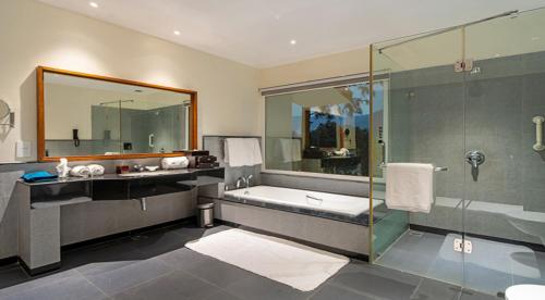 a bathroom with a tub and a glass shower at Moksha Himalaya Spa Resort in Kasauli