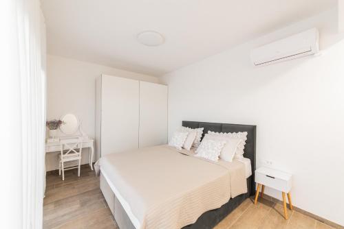 a white bedroom with a bed and a desk at Villa Cardellino in Klis