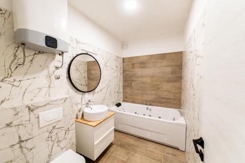 a bathroom with a tub and a sink and a mirror at Villa Cardellino in Klis