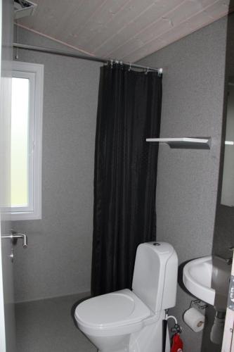 a bathroom with a toilet and a black shower curtain at Læsø Camping & Hytteby in Vesterø Havn