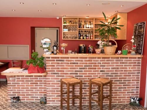a bar with two stools in front of a brick wall at Logis Auberge du Valburgeois in Sainte-Gauburge-Sainte-Colombe