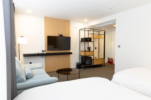ein Zimmer mit einem Bett, einem Fernseher und einer Couch in der Unterkunft Southernheal Hotel in Haenam