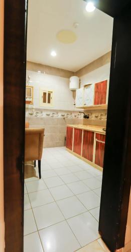 a kitchen with a table and a white tile floor at شقق القنفذة بلس in Al Qunfudhah