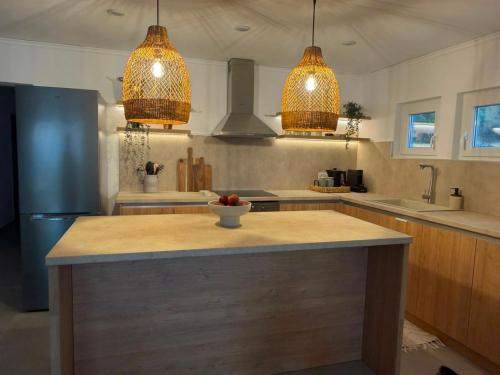 a kitchen with a island with a bowl of fruit on it at Aegean Horizon Seafront Luxury Villa Plomari Garden Level in Trýgonas