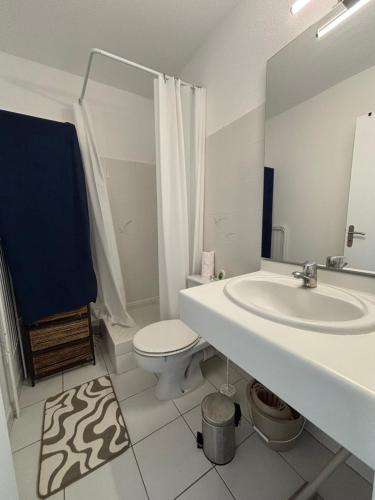 a white bathroom with a sink and a toilet at Le TAHITI in Frontignan