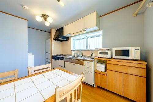 a kitchen with a table and a microwave at Hale Kai Akiya in Yokosuka