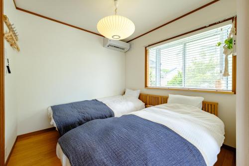 two beds in a room with a window at Hale Kai Akiya in Yokosuka