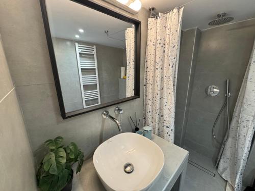 a bathroom with a sink and a shower and a mirror at Cosy Stay in Platamonas