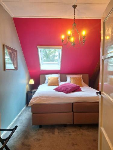 a bedroom with a pink wall with a bed at Hof van Eden in Ophemert
