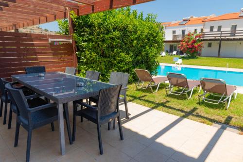 a patio with a table and chairs next to a pool at Villa Kadrina in Kolymbia