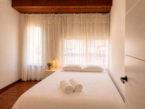 a bedroom with a white bed with two towels on it at Urban Hub in A Coruña