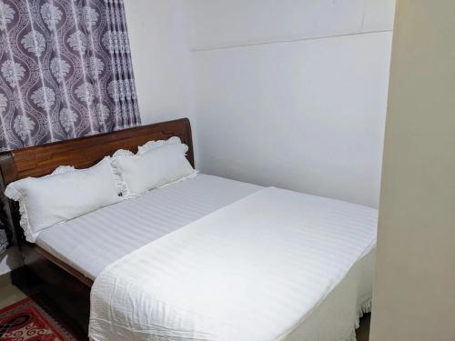 a bedroom with a bed with white sheets at Chris Hotel in Runda