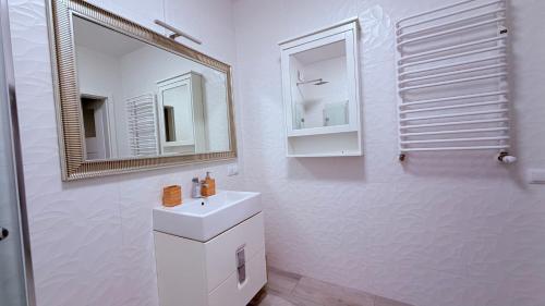 a white bathroom with a sink and a mirror at Azymut in Darłowo
