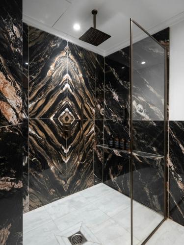 a bathroom with a shower with black marble at Regency Suite Hotel in Lahore
