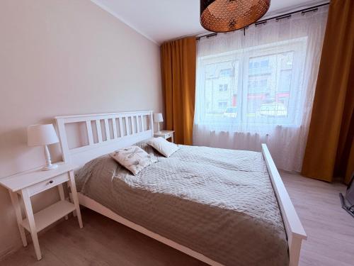 a white bedroom with a bed and a window at Azymut in Darłowo
