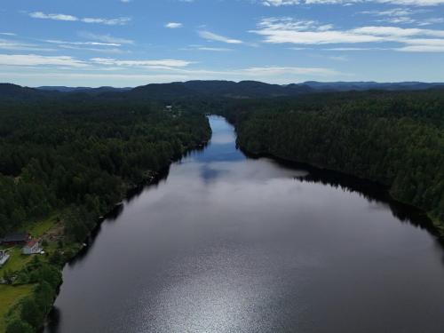 an aerial view of a river with trees on both sides at hytte ved innsjø in Skien
