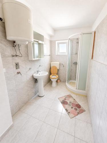 a bathroom with a toilet and a shower and a sink at Holiday home Moni in Karlobag