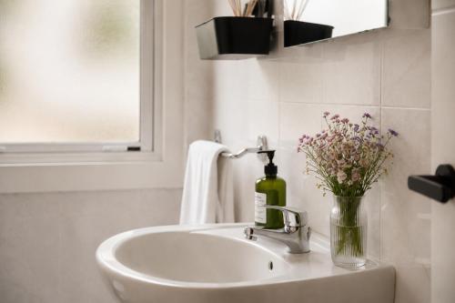 a bathroom sink with a bottle of wine and flowers at Urban Hub in A Coruña