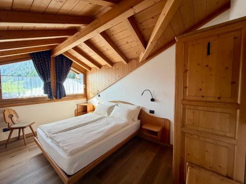 a bedroom with a bed in a room with wooden ceilings at Rosengarden Alpine Residence in Valdidentro