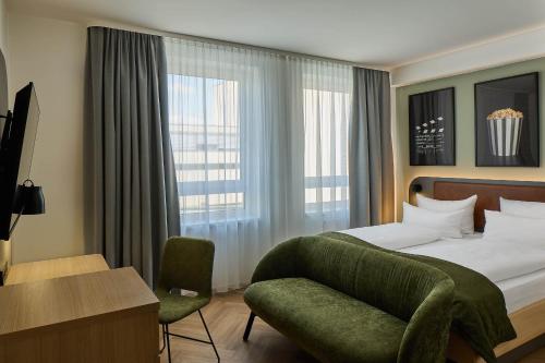 a bedroom with a bed and a chair and a window at Cinema City Hotel Europaplatz Karlsruhe - Brand New Boutique Hotel 2025 - in Karlsruhe