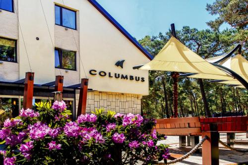 a building with a bench and flowers in front of it at Columbus Rowy in Rowy