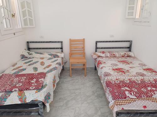 a room with two beds and a wooden chair at HASH # SAAd in Marsa Matruh