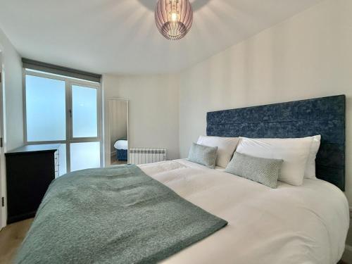 a bedroom with a large white bed with a blue headboard at Apartment 299 - Clifden in Clifden