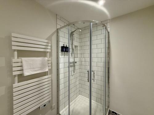 a glass shower in a bathroom with white tiles at Apartment 299 - Clifden in Clifden