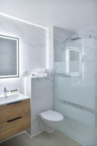 a white bathroom with a toilet and a shower at Hôtel Les Comtes de Pardiac in Marciac