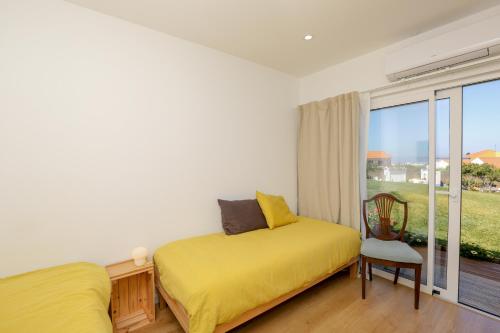 a bedroom with a yellow bed and a window at Like-home-T2 house, pool, AC, garden in Ericeira