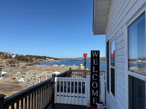 a balcony of a house with a view of the water at The Wild Rose Cottage & Bird's Nest in Twillingate