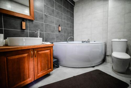a bathroom with a tub and a toilet and a sink at Hotel Serdar in Mojkovac