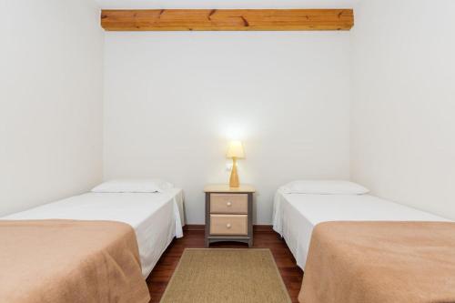 Habitación con 2 camas y mesa con lámpara. en Cal Cinque, en La Seu d'Urgell