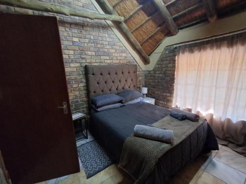 a bedroom with a large bed and a brick wall at Bushveld Bliss in Marloth Park
