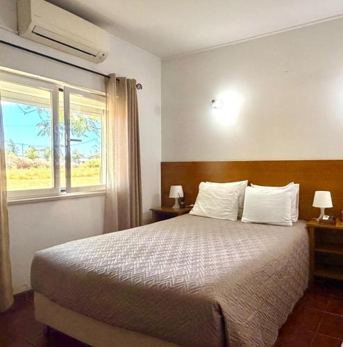 a bedroom with a large bed and a window at Retiro dos Batudes in Palmela