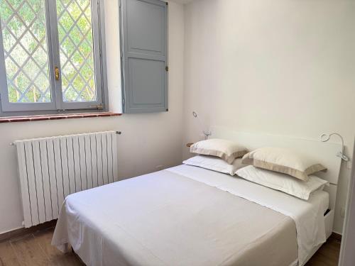 a white bed in a room with two windows at Casa della Consolazione in Todi