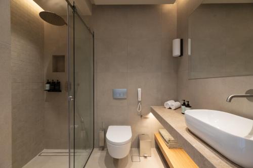 a bathroom with a sink and a toilet and a shower at Pefkian Ethos Hotel & Suites in Pefki