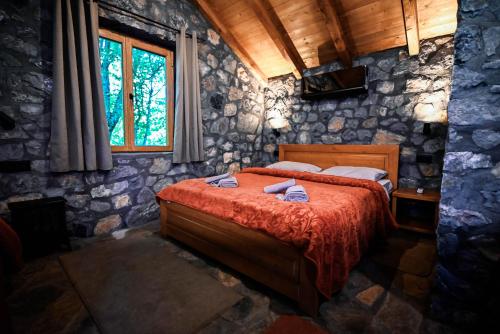 a bedroom with a bed in a stone wall at Hotel Serdar in Mojkovac