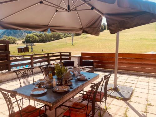 a table with an umbrella on a patio at Le Logis de Bamby in Ancelle