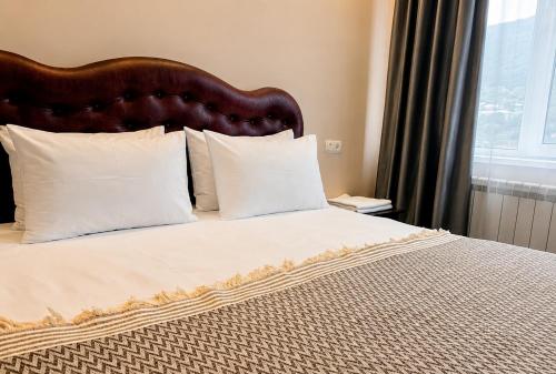 a bed with a wooden headboard and white pillows at Mina Hotel in Goris
